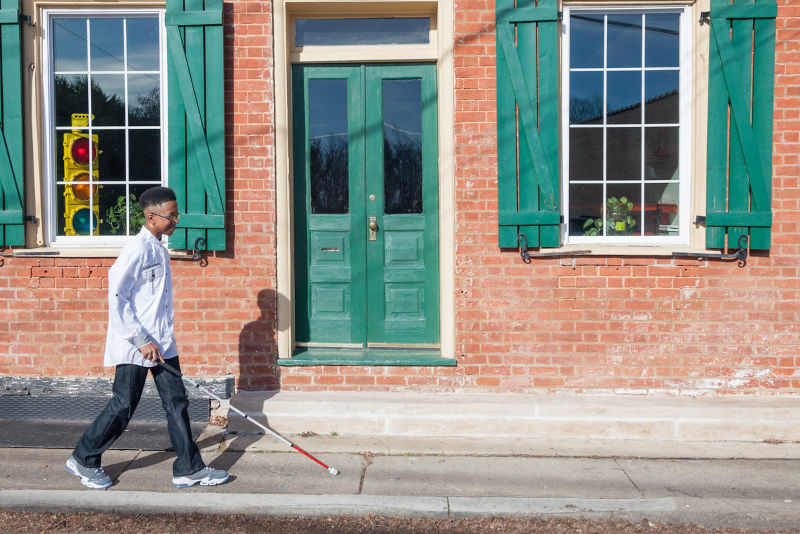 Student on sidewalk with cane