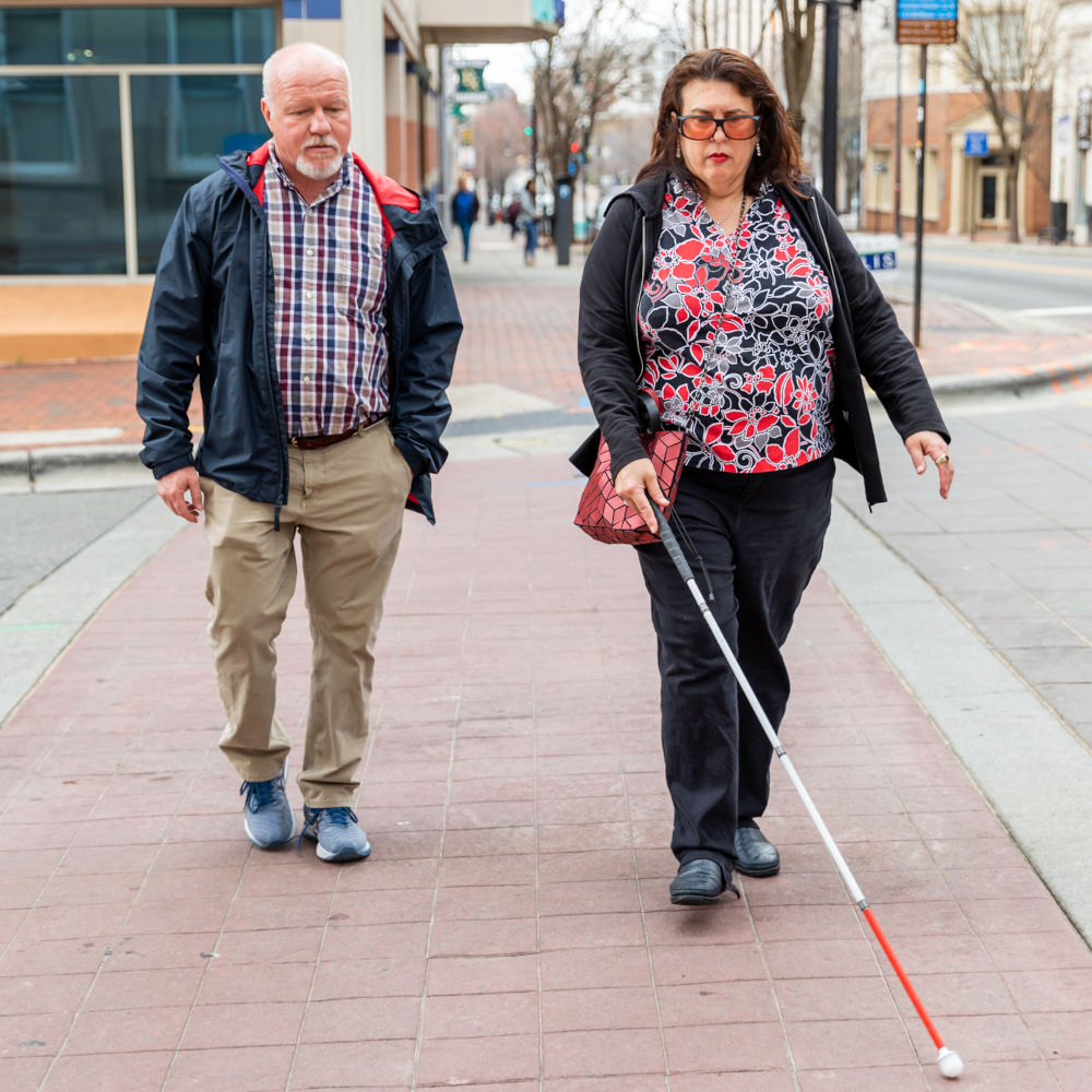 Adult with white cane crossing street